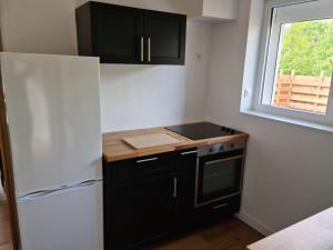 a kitchen with black cabinets and a white refrigerator at Le calme de la nature à 8 minutes des plages in Sémussac