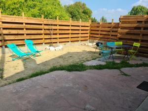 een patio met stoelen, een tafel en een hek bij Le calme de la nature à 8 minutes des plages in Sémussac