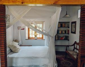 a bedroom with a canopy bed with a window at The Cottage in Prince Albert