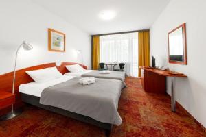 ein Hotelzimmer mit zwei Betten und einem Schreibtisch in der Unterkunft Ośrodek Wypoczynkowo-Rehabilitacyjny "Bryza" in Dźwirzyno + 24 Fotos