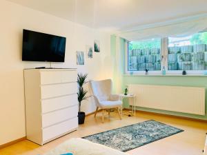 sala de estar con TV y tocador blanco en Ferienwohnung Elsa - Parkplatz, Küche, WLAN, ruhige Lage, en Malterdingen