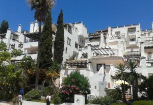 een groot wit gebouw met bomen ervoor bij Penthouse at Pueblo Evita in Benalmádena