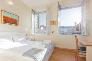 a bedroom with a bed and a desk and two windows at Milan Retreats Cadorna Duomo in Milan