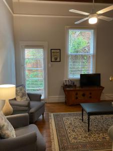 a living room with a couch and a table and two windows at Kilparney House in Benalla