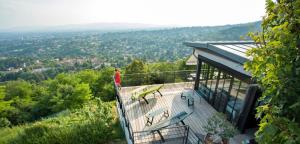 une personne debout sur le balcon d'une maison dans l'établissement L'Ermitage Hôtel Cuisine-À-Manger, à Saint-Cyr-au-Mont-dʼOr