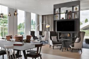 een woonkamer met een tafel en stoelen en een televisie bij Stellaris Apartment Hotel in Garching bei München