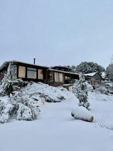 ein schneebedecktes Haus mit Bäumen davor in der Unterkunft Nomad Hostel in Nimrod
