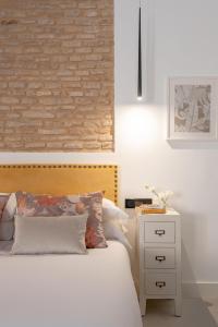 1 dormitorio con cama blanca y pared de ladrillo en Hommyhome Conteros Cathedral Apartments, en Sevilla