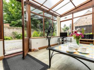 a conservatory with a glass table in a room with windows at The Georgian Cottage in Bedale