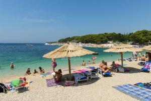 a group of people on a beach with umbrellas at Rooms Bozena in Primošten