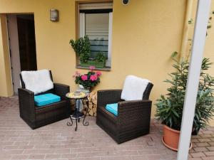 2 chaises en osier et une table sur la terrasse dans l'établissement Ferienwohnung Würzburg/Heidingsfeld, à Wurtzbourg