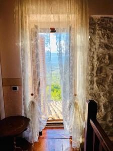 Pacentro Dimora del Castello في Pacentro: نافذة ذات ستائر بيضاء وطاولة وإطلالة