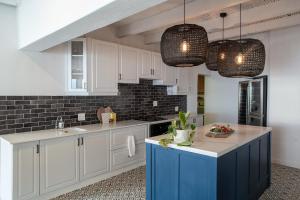 una cocina con armarios blancos y una isla azul en Villa Marine Guest House, en Pringle Bay