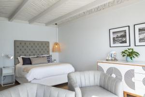 Villa Marine Guest House في خليج برينغل.: غرفة نوم بيضاء بسرير وكرسي