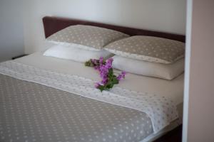 a bed with white pillows and purple flowers on it at Spa Resort Luxury Apartments in Budva +34 photos
