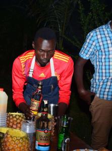 Un uomo è in piedi accanto a un tavolo con bevande di Sipi Valley Resort a Mbale