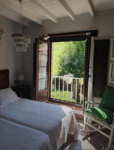 a bedroom with a bed and a window and a chair at La Gesta Picos de Europa in Poo de Cabrales