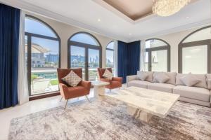 a living room with a couch and chairs and windows at SOL Living - Exquisite 5BR Garden Villa w/Pool & Beach in Palm in Dubai