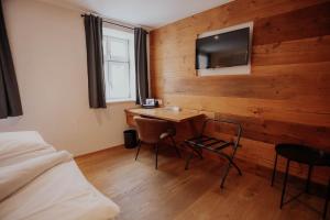 ein Schlafzimmer mit Schreibtisch und Fernseher an einer Holzwand in der Unterkunft Altstadtmittehotel Sonne in Dinkelsbühl