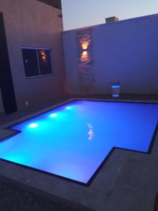 uma grande piscina com iluminação azul num quarto em Casa Marilago em Camocim