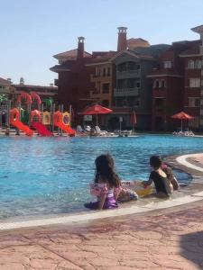 2 enfants assis dans un parc aquatique dans l'établissement porto sharm 2 bed room and private garden-pool view, à Charm el-Cheikh