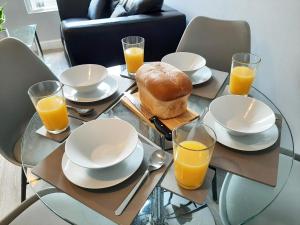 a glass table with plates and glasses of orange juice at Malton Central Apartments in Malton