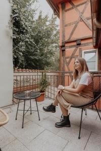 une femme assise dans une chaise sur une terrasse couverte dans l'établissement Hotel Gasthaus zur Sonne, à Dinkelsbühl