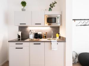 a kitchen with white cabinets and a microwave at limehome Frankfurt Gutleutstraße - Digital Access in Frankfurt/Main