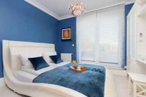 niebieska sypialnia z białym łóżkiem i żyrandolem w obiekcie Sailor Apartment Jastrzębia Góra by Renters Prestige w Jastrzębiej Górze