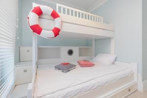 białe łóżko piętrowe z czerwono-białym urządzeniem ratunkowym w obiekcie Sailor Apartment Jastrzębia Góra by Renters Prestige w Jastrzębiej Górze