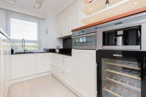 kuchnia z białymi szafkami i czarnymi urządzeniami w obiekcie Sailor Apartment Jastrzębia Góra by Renters Prestige w Jastrzębiej Górze