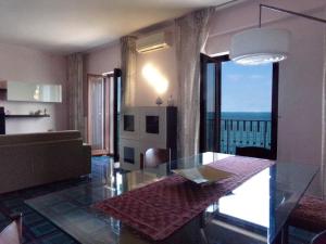 een woonkamer met een glazen tafel en uitzicht op de oceaan bij Fronte Mare in Molfetta