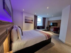 um quarto de hotel com uma cama com iluminação roxa em Escape Hotel em Barrow in Furness