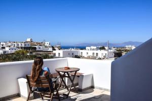 a woman sitting at a table on the balcony of a house at Hotel Kastelakia Mykonos in Mýkonos City