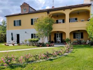 ein großes gelbes Haus mit Blumen im Hof in der Unterkunft Bed&Breakfast Villa Camilla in Ivrea