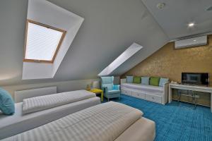 a attic room with two beds and a tv at Hotel Pod Bránou in Bardejov