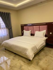 1 dormitorio con 1 cama grande y cabecero rosa en شقق القارات السبع الاحساء, en Al Hofuf