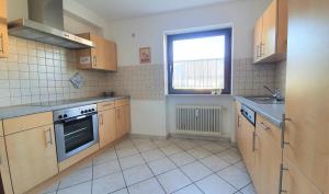 a kitchen with wooden cabinets and a window at Gästehaus Reinke - nahe Europa-Park in Ettenheim +3 photos