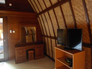 sala de estar con TV y espejo en Sandy Beach Bungalows, en Gili Air