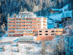 a large building in the snow with a mountain at Panorama SPA Aparthotel Schillerhof by AlpenTravel in Bad Gastein