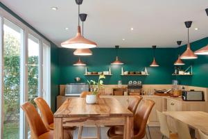 cocina con mesa de madera y pared verde en Aparthotel Adagio Access Carrières Sous Poissy, en Carrières-sous-Poissy