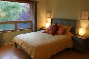 1 dormitorio con cama y ventana grande en Five Elements Lodge B&B with Outdoor Spa en Fernwood