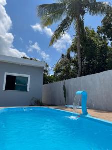 a blue swimming pool with a water fountain at Casa de praia em Barra do Gil in Vera Cruz de Itaparica