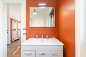 ローマにあるB&B Il Giardino di Gabriの白いシンクとオレンジ色の壁が備わるバスルーム