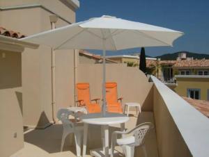 een tafel en stoelen met een parasol op een balkon bij Casa Del Mar - Beautiful Two Bedroom Penthouse Apartment in Sainte-Maxime