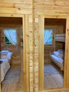 two beds in a log cabin with two windows at Dubryk Domki na Kaszubach in Stara Kiszewa