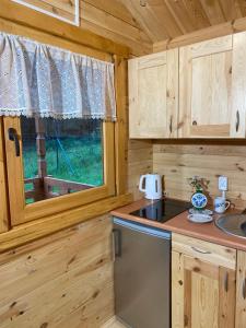 a kitchen with a stove and a window in a log cabin at Dubryk Domki na Kaszubach in Stara Kiszewa