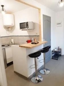 a kitchen with a counter and two bar stools at Le Petit Charmeur, parking, Wifi, gare in Flers