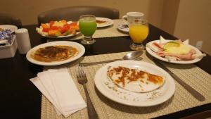 a table with plates of breakfast food and drinks at Beach Class Convention By Mai in Recife