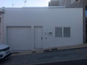 ein weißes Gebäude mit zwei Garagentüren und einem Auto in der Unterkunft Casa Blanca La Restinga in La Restinga